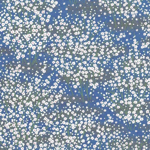 Japanese screen printed decorative chiyogami paper used in handmade cards. A blue paper covered with a dense pattern of small white flowers and a few muted green stems.