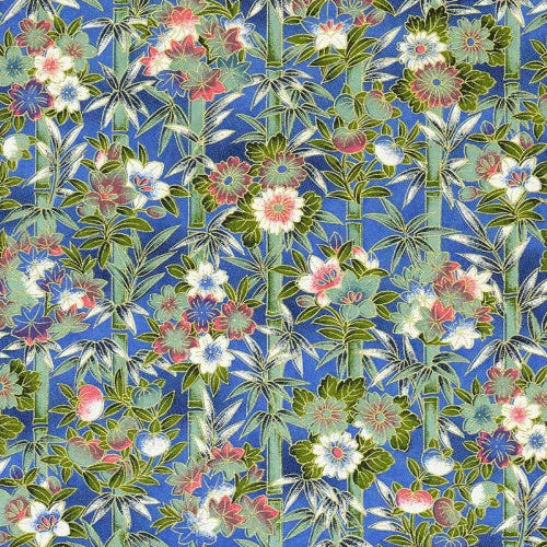 Japanese screen printed decorative chiyogami paper used in handmade cards. A repeating floral and bamboo pattern on a blue fabric or wallpaper background, with green leaves, pink and white blossoms, and small blue accents.